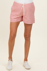 woman wearing a red and white striped maternity short with drawstring waist and white sneakers