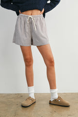 woman wearing striped drawstring shorts with a cozy sweater and beige slip-on shoes