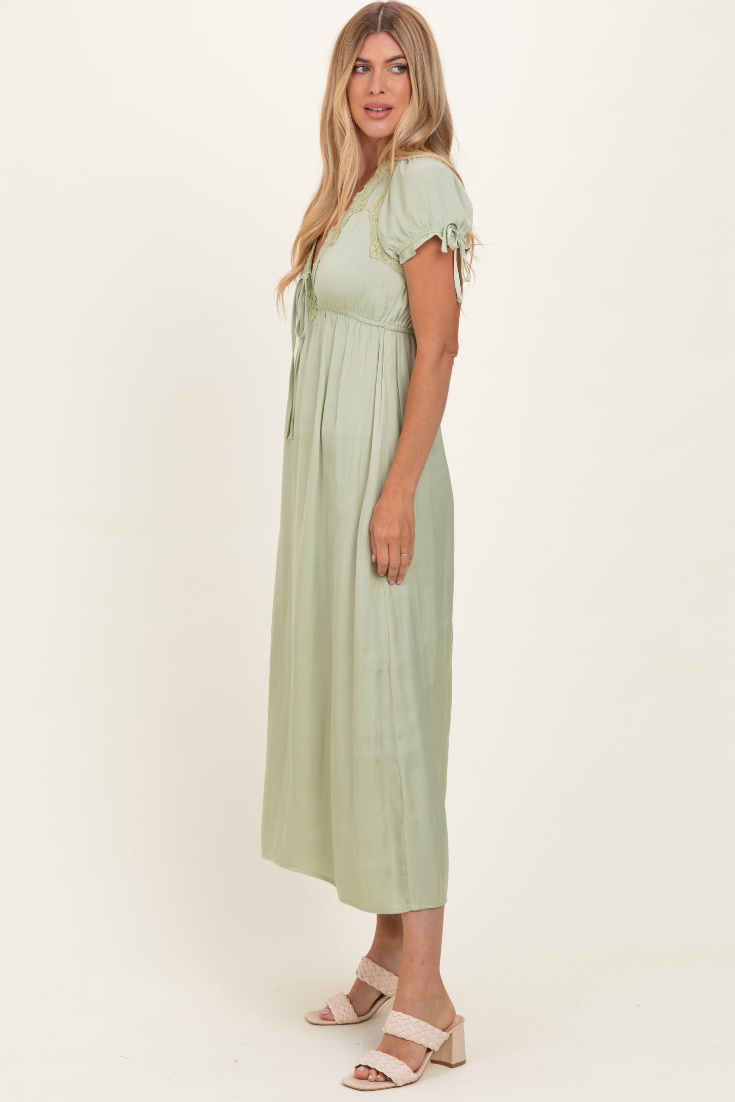 woman wearing a light green maxi dress with puff sleeves and a drawstring front detail