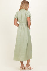 woman wearing a light green maxi dress with short sleeves and tie details at the shoulders, seen from the back