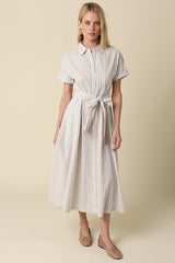 woman wearing a striped midi shirt dress with buttons and a tie waist, styled with flat shoes