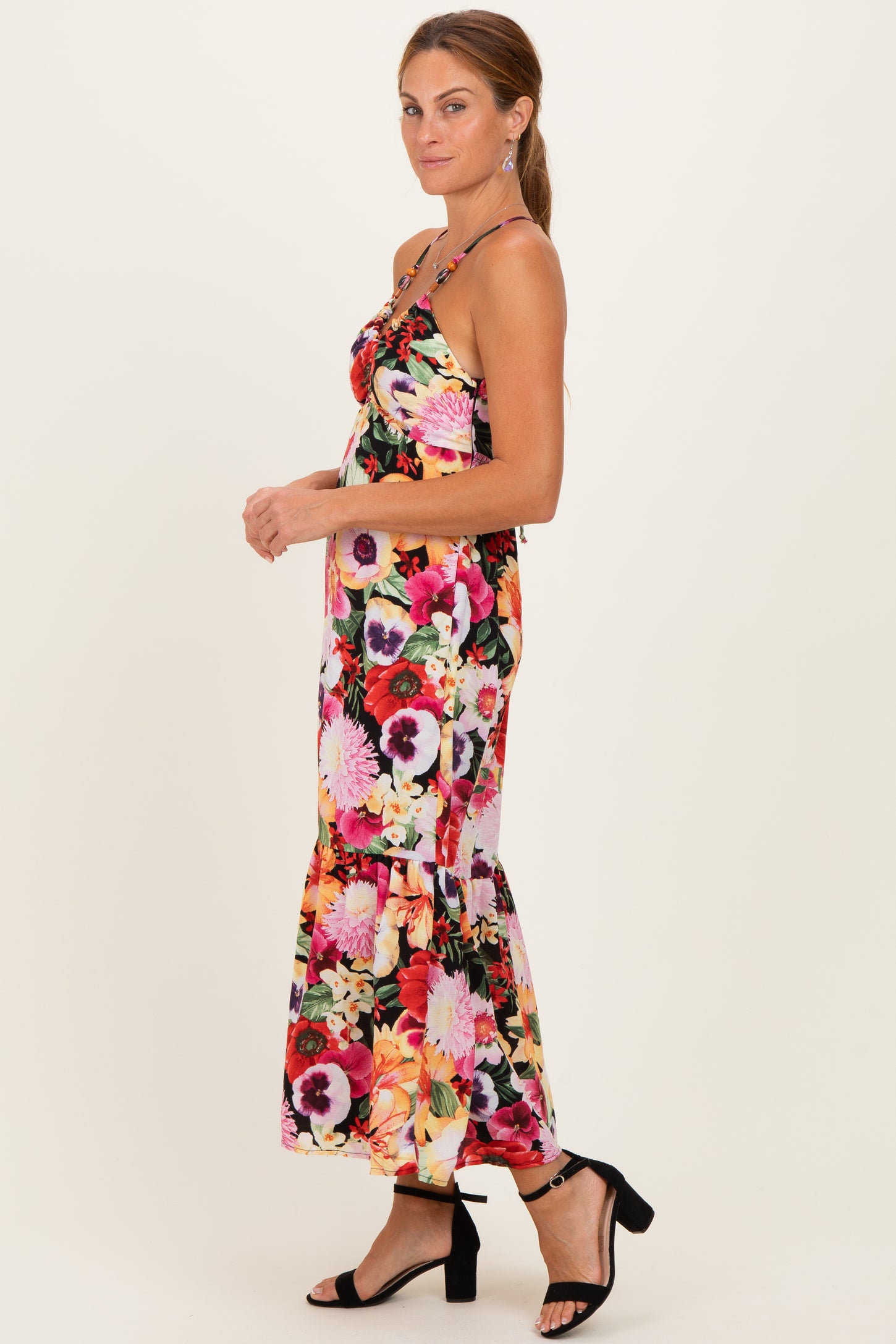 woman wearing a floral maxi dress with spaghetti straps and a ruffled hem, paired with black strappy heels