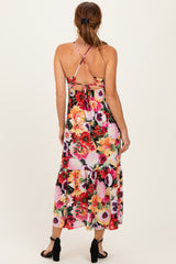 woman wearing a floral maxi dress with a tie back and spaghetti straps, showing a vibrant array of flowers