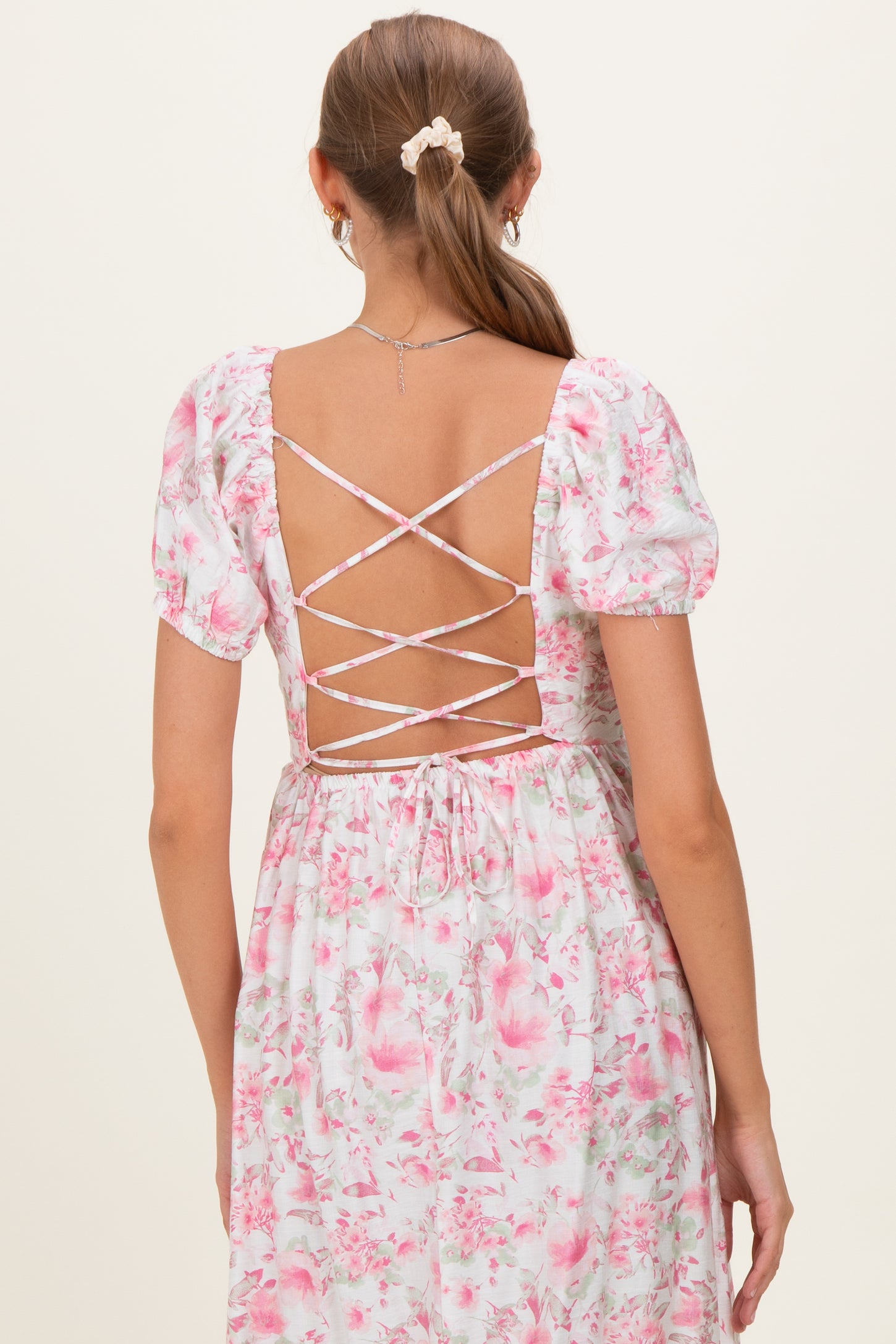 woman wearing a floral pink maternity dress with a crisscross back detail and puff sleeves