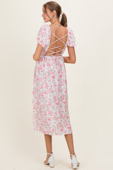 woman wearing a pink floral maternity dress with a lace-up back and short puff sleeves