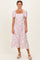 woman wearing a white floral midi dress with puff sleeves and a square neckline, standing against a neutral background