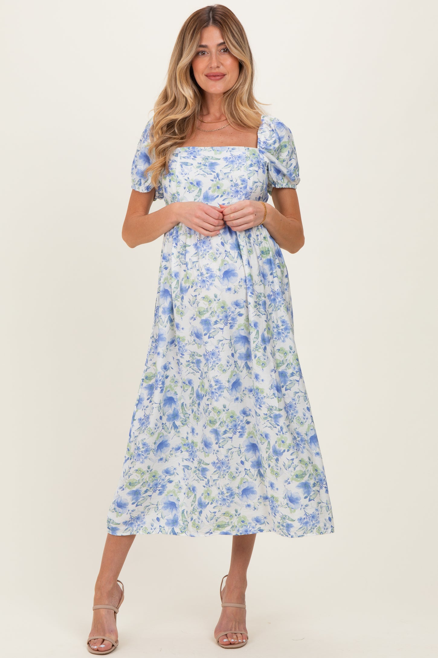 woman wearing a floral blue and white maternity dress with short puff sleeves and a square neckline