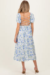 woman wearing a floral backless maternity dress with puff sleeves and lace-up detail, showcasing a baby bump