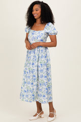 woman wearing a floral midi dress with short puff sleeves and a square neckline in blue and green tones