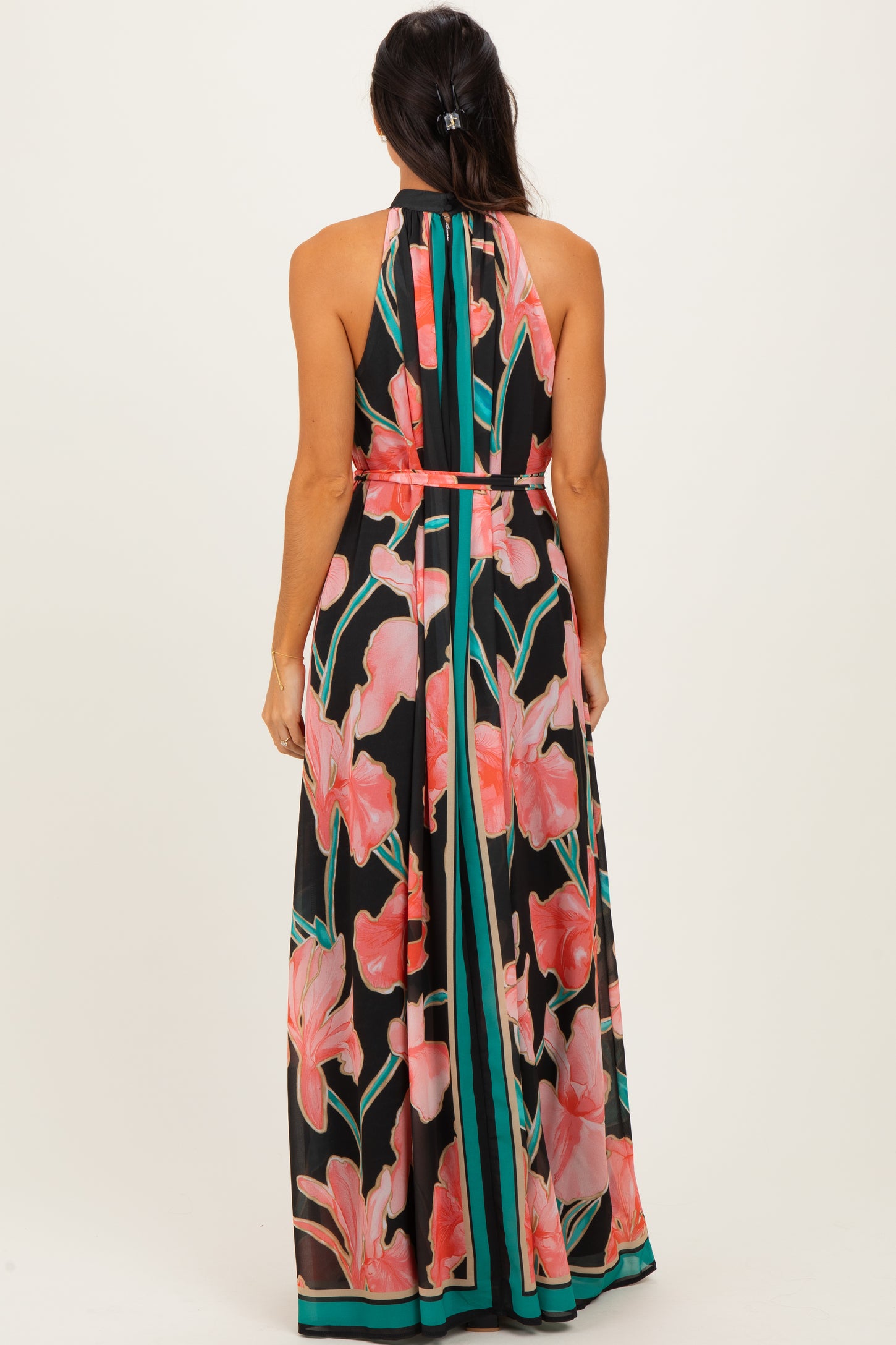 woman wearing a black halter neck maxi dress with a vibrant floral print and contrasting striped details