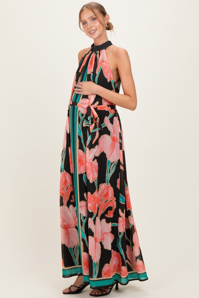 woman wearing a black floral maternity maxi dress with a halter neckline and holding her baby bump