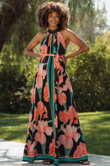 woman wearing a black floral maternity maxi dress with a halter neck and tie waist, showcasing her baby bump
