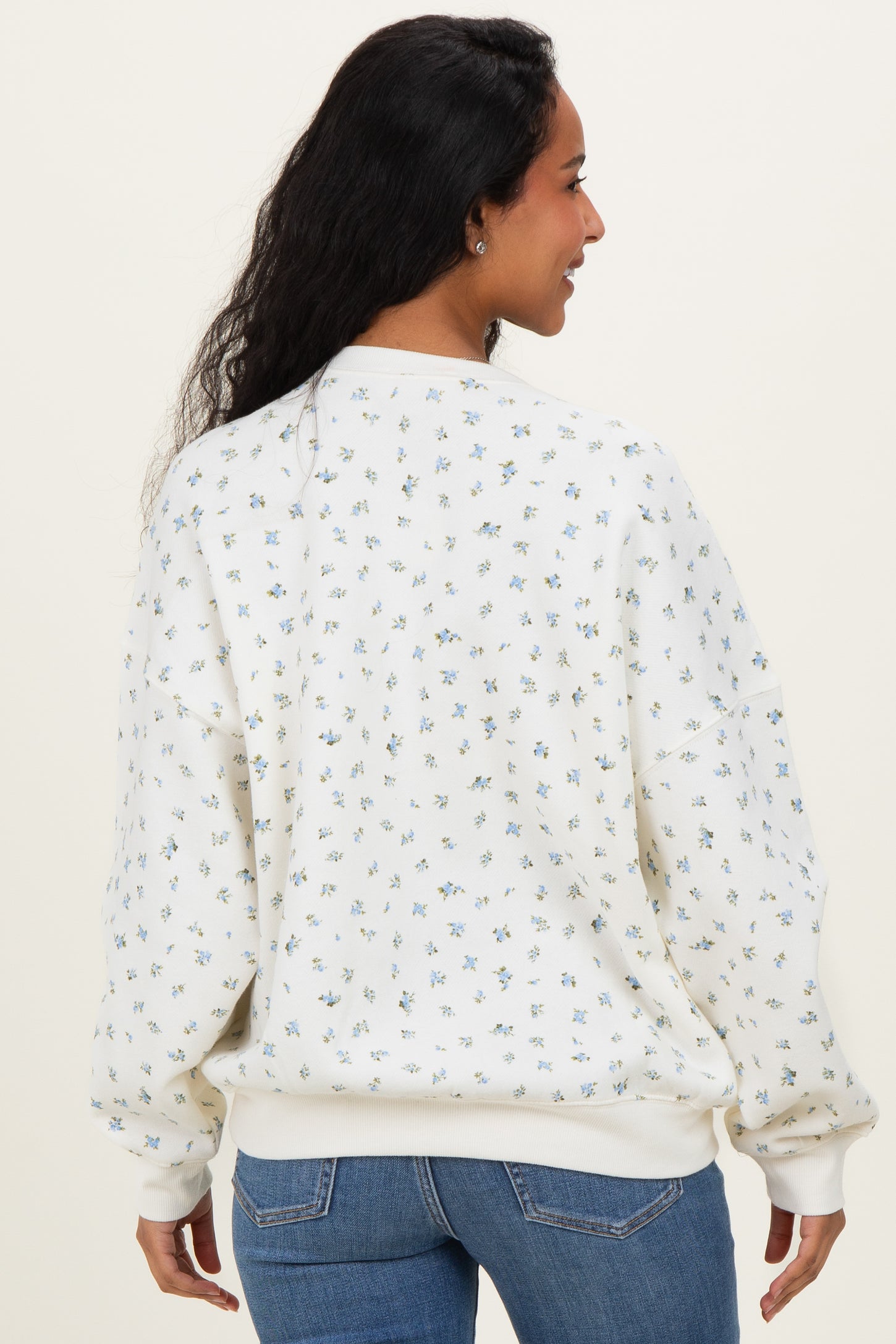 woman wearing a white floral-patterned maternity sweatshirt with a relaxed fit, showing a baby bump from the back