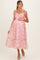 woman wearing a pink floral maternity dress with ruffled sleeves and a flowing skirt, showcasing her baby bump