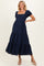 woman wearing a navy blue maternity dress with short puff sleeves and a tiered, embroidered skirt, showing her baby bump