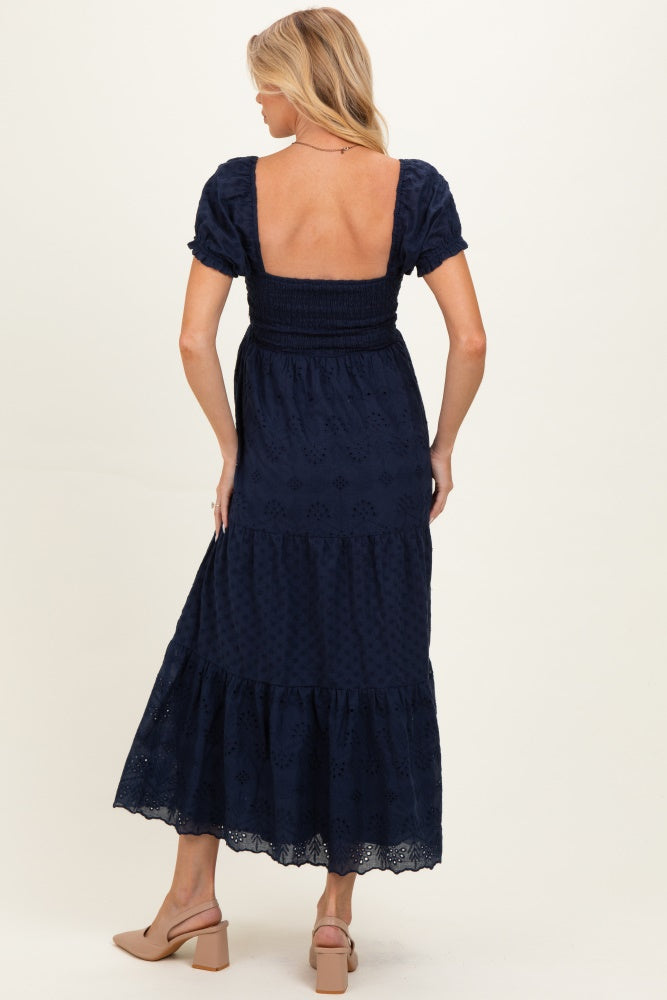 woman wearing a navy blue maternity maxi dress with short puff sleeves and tiered skirt, showing a relaxed fit