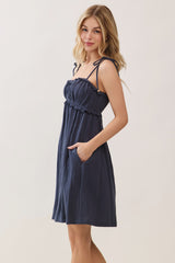 woman wearing a navy blue sleeveless dress with adjustable straps and pockets