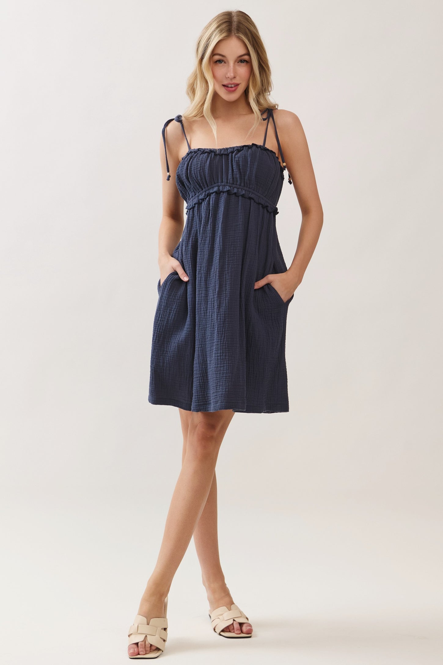 woman wearing a navy blue sundress with adjustable straps and front pockets