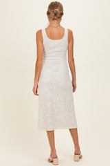 woman wearing a white lace maternity dress, viewed from the back, with a fitted style and midi length