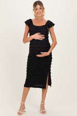 woman wearing a black ruffled maternity dress with a side slit and holding her baby bump