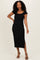woman wearing a black midi dress with tiered ruffle details and short sleeves, standing with one hand on her hip