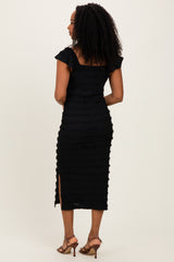 woman wearing a black fitted midi dress with ruffle details and a thigh-high slit, shown from the back