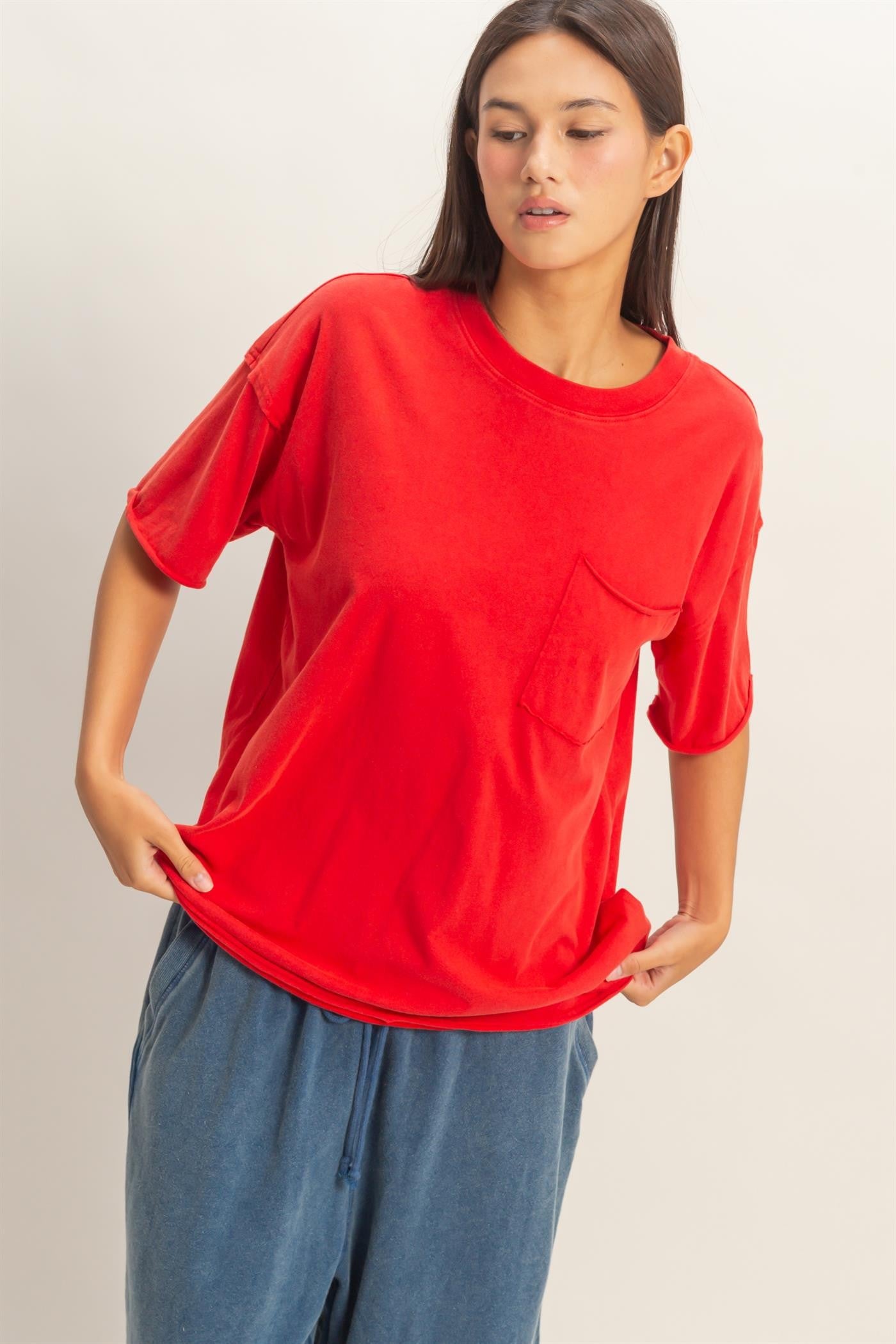 woman wearing a vibrant red oversized t-shirt with a front pocket paired with loose blue pants
