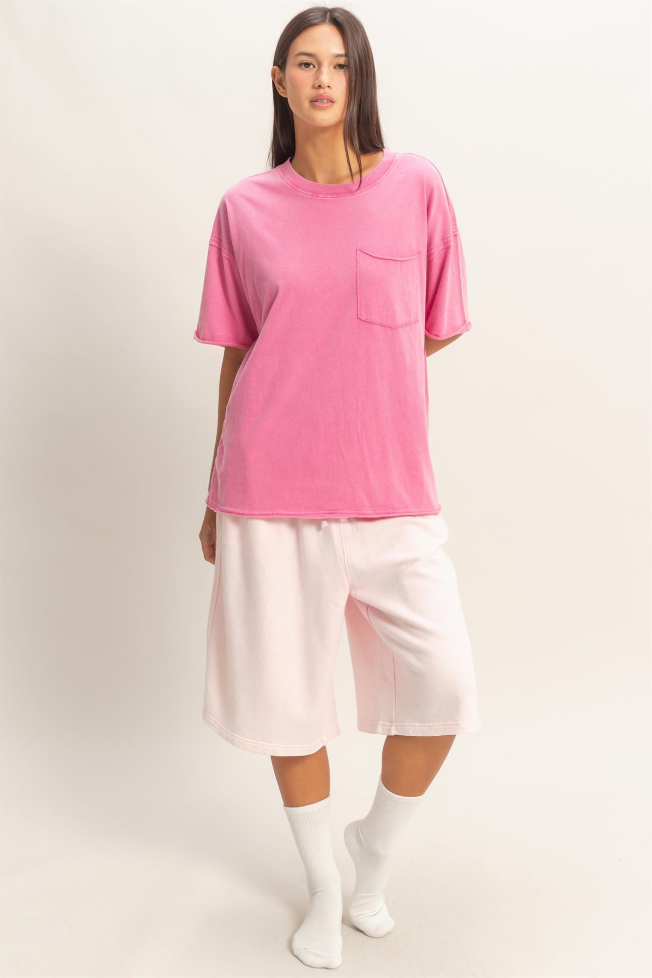 woman wearing a pink oversized t-shirt with a pocket and white knee-length shorts