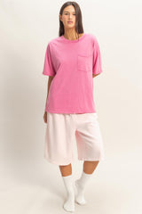 woman wearing a pink oversized t-shirt with a pocket and white knee-length shorts