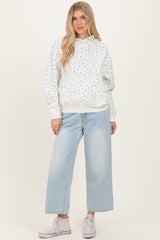 woman wearing a white hoodie with blue floral print and light wash wide-leg jeans