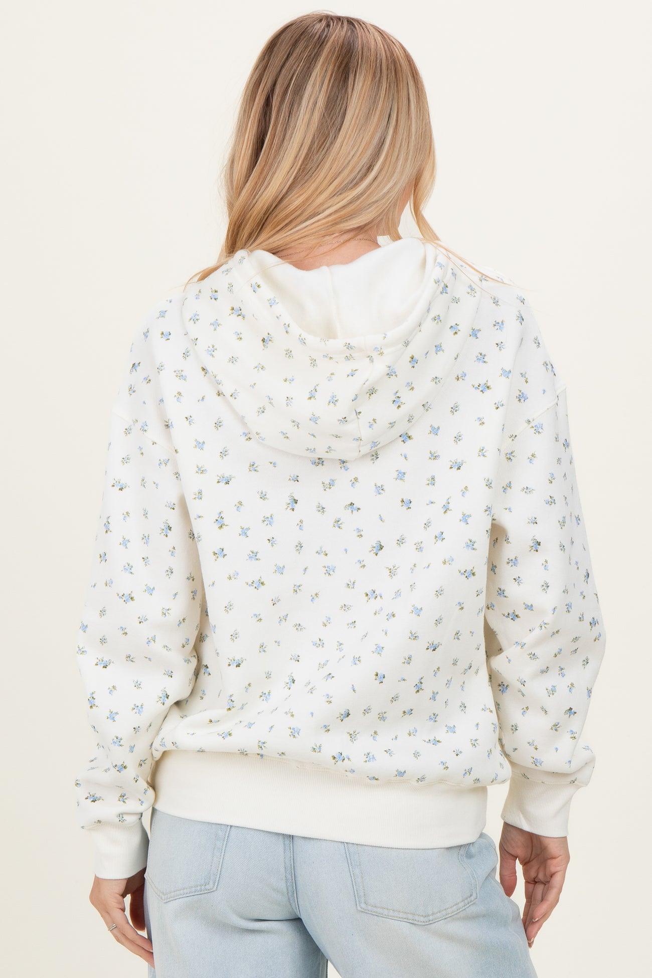 woman wearing a white hoodie with small floral prints and a relaxed fit, shown from the back