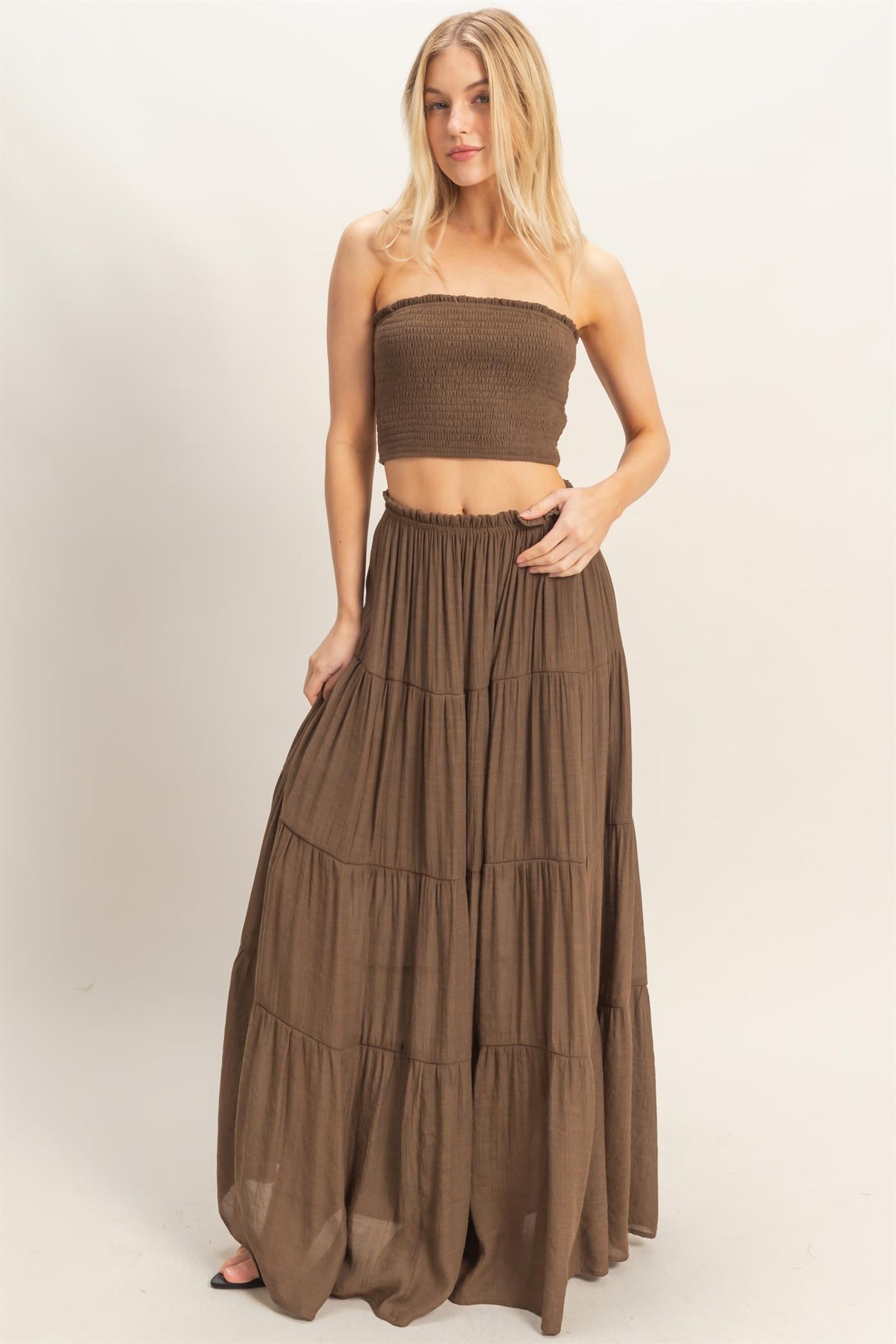 woman wearing a brown smocked bandeau top and a long tiered maxi skirt