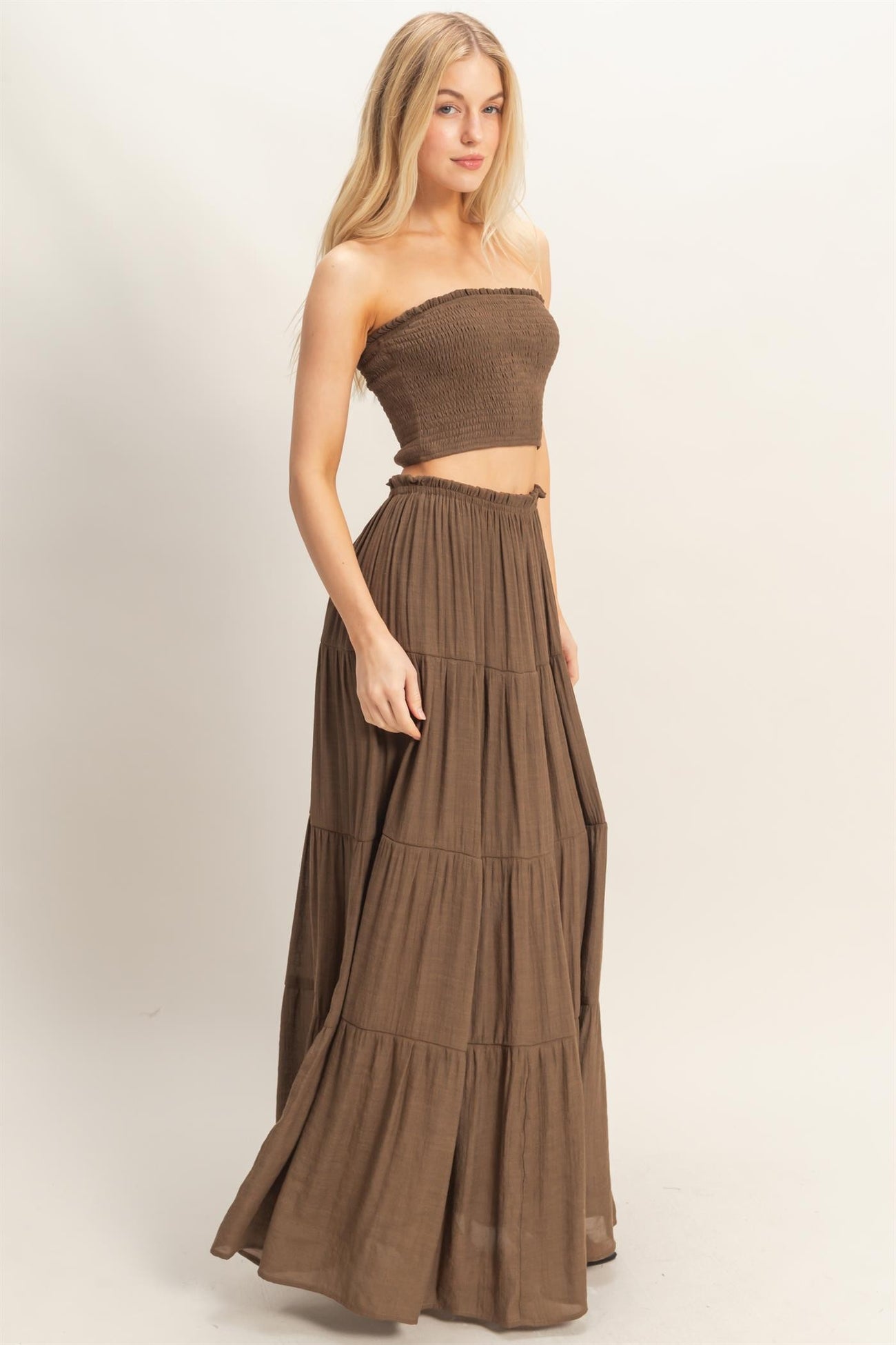 woman wearing a brown strapless smocked crop top and a matching tiered maxi skirt