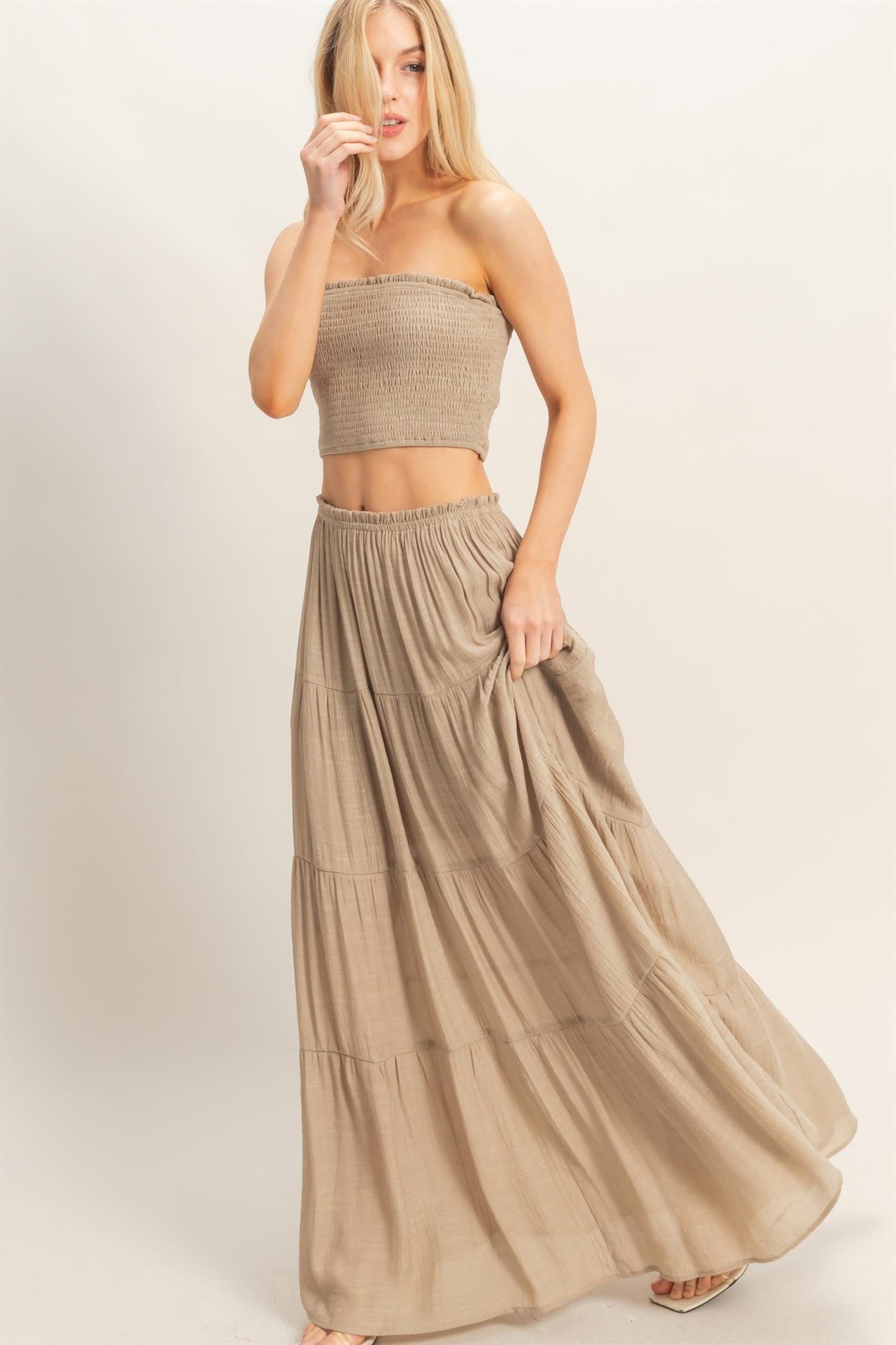 woman wearing a beige smocked crop top and matching tiered maxi skirt