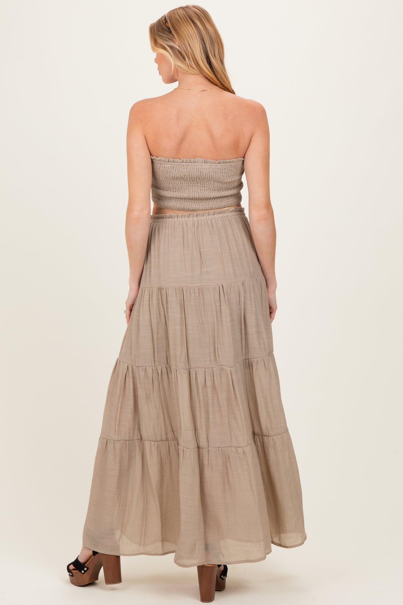 back view of a woman wearing a brown strapless maternity maxi dress with tiered ruffles