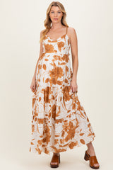 woman wearing a white maternity maxi dress with orange floral print and holding her baby bump