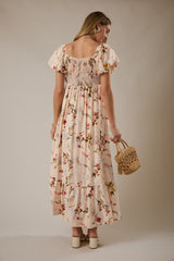 woman wearing a floral maxi dress with puff sleeves and a smocked back, holding a woven straw handbag
