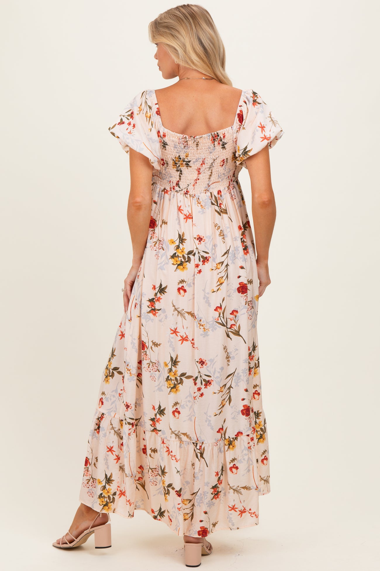 woman wearing a floral maternity maxi dress with puff sleeves and a smocked back, showcasing a baby bump