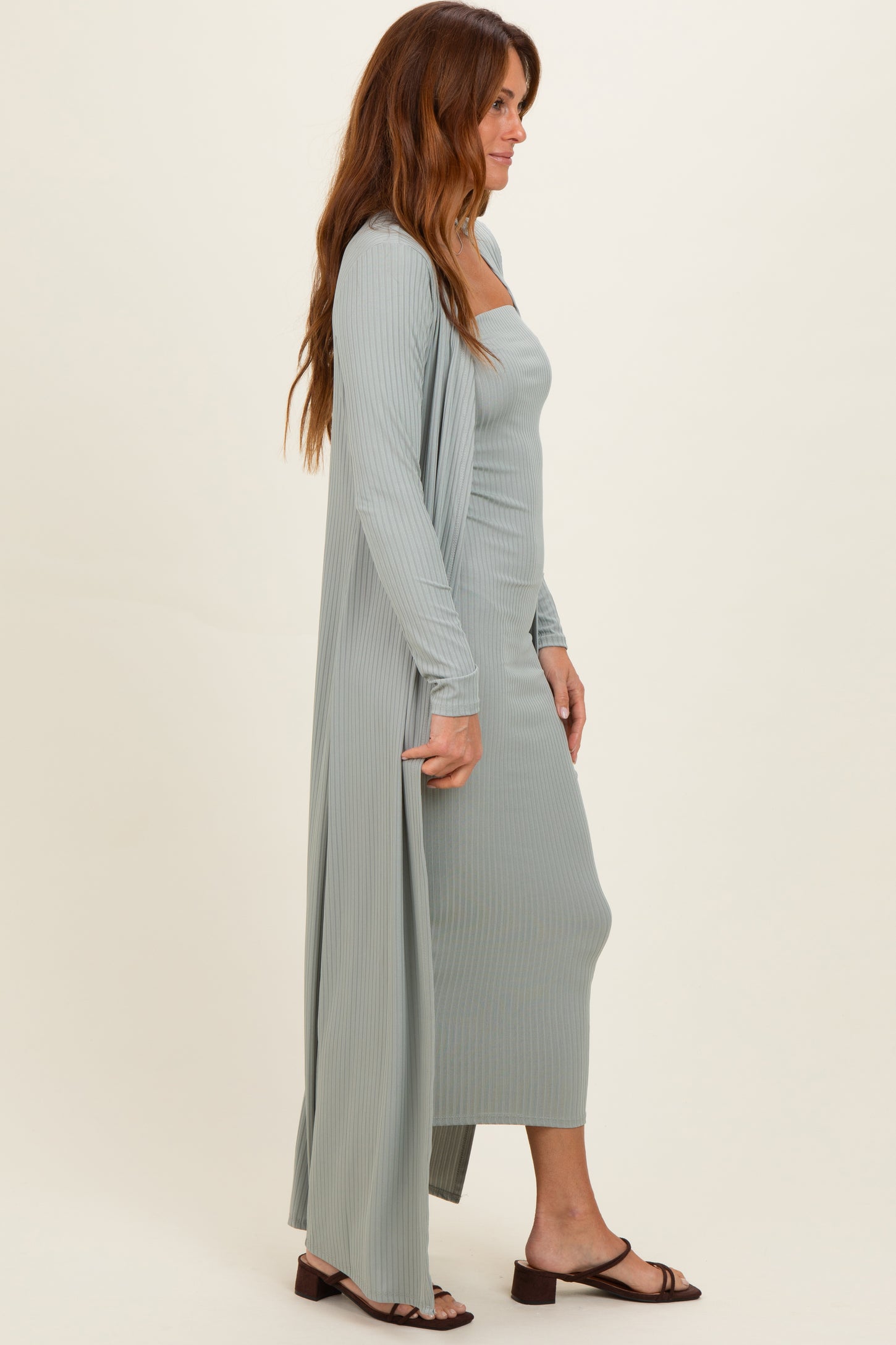 woman wearing a light green ribbed midi dress with a matching long cardigan and brown sandals