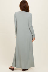 woman wearing a long sage green ribbed maxi dress with long sleeves and side slits