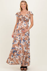 woman wearing a brown floral maternity maxi dress, holding her baby bump with a smile