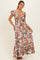 woman wearing a brown floral maxi dress with ruffle sleeves and a knotted front detail