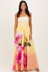 woman wearing a strapless yellow maxi dress with pink floral pattern