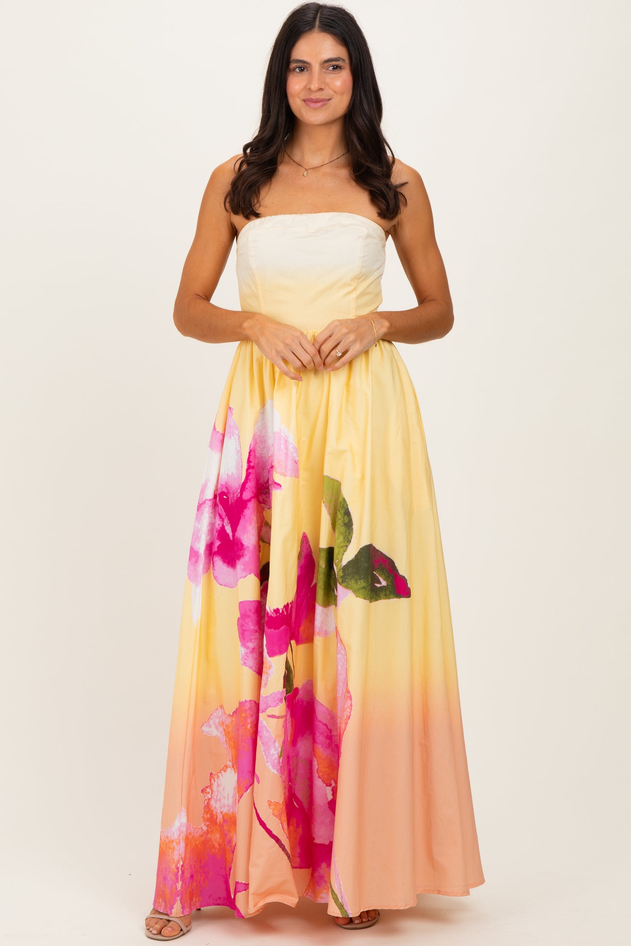 woman wearing a strapless yellow maxi dress with large pink floral print
