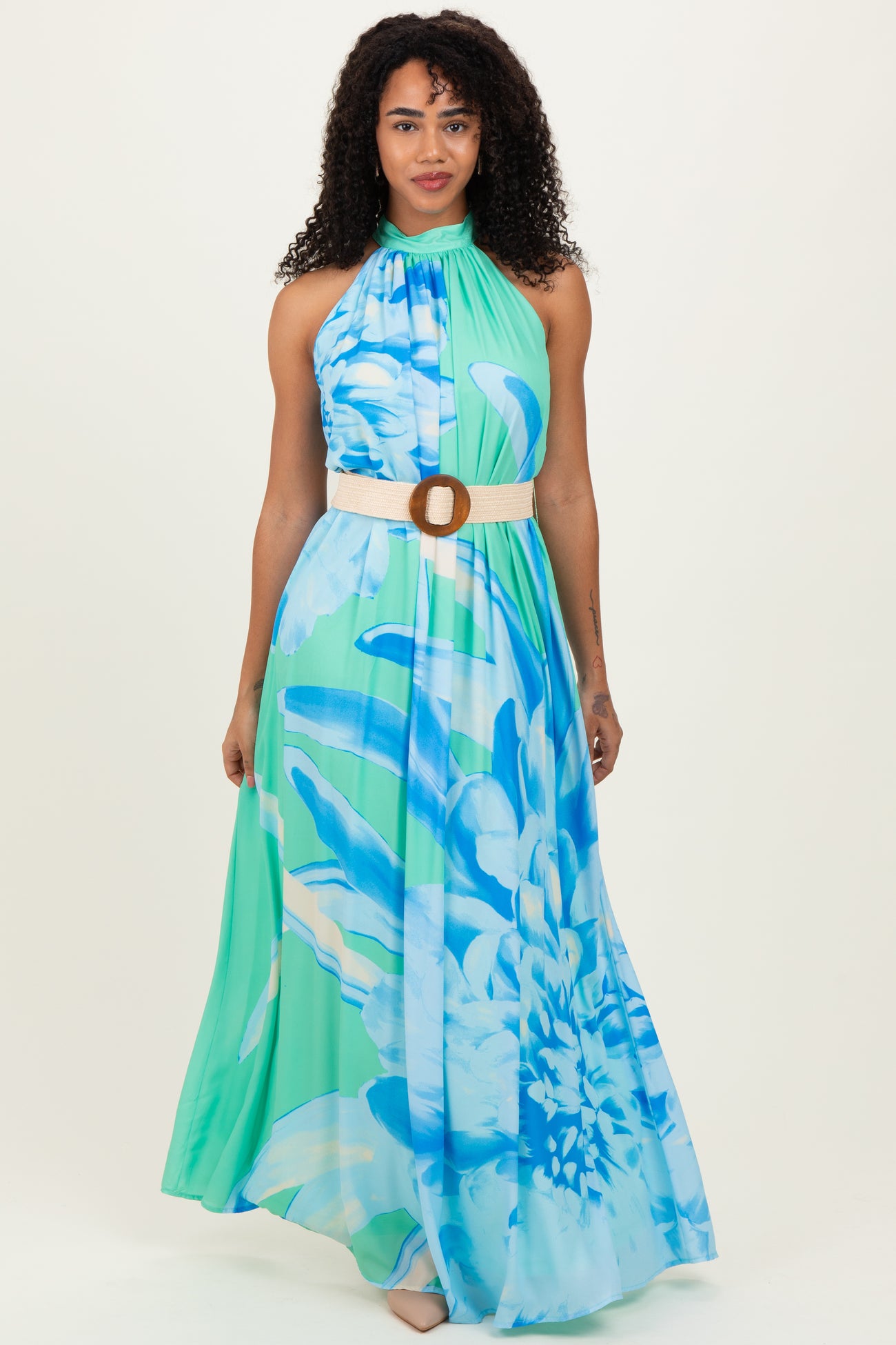 woman wearing a blue and green floral maxi dress with a halter neck and a wide tan belt