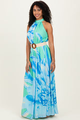 woman wearing a blue and green floral maxi dress with a halter neckline and a belt at the waist
