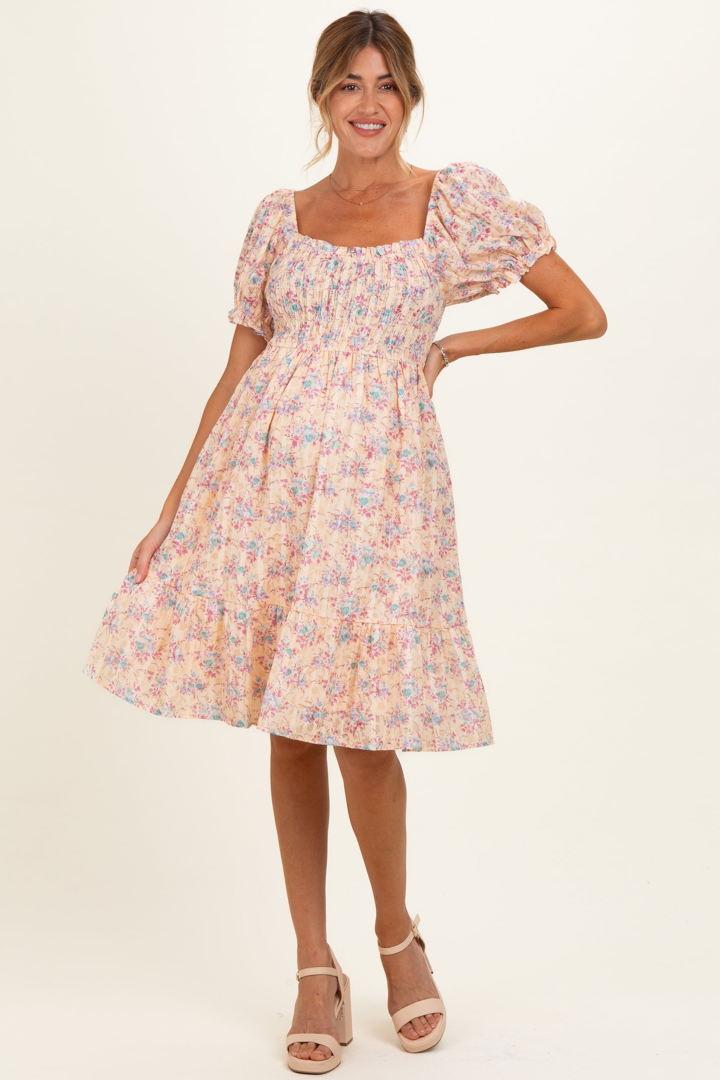 woman wearing a floral pink maternity dress with puff sleeves and a fitted bodice, showcasing her baby bump