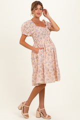 woman wearing a floral pink puff sleeve maternity dress with pockets and a visible baby bump