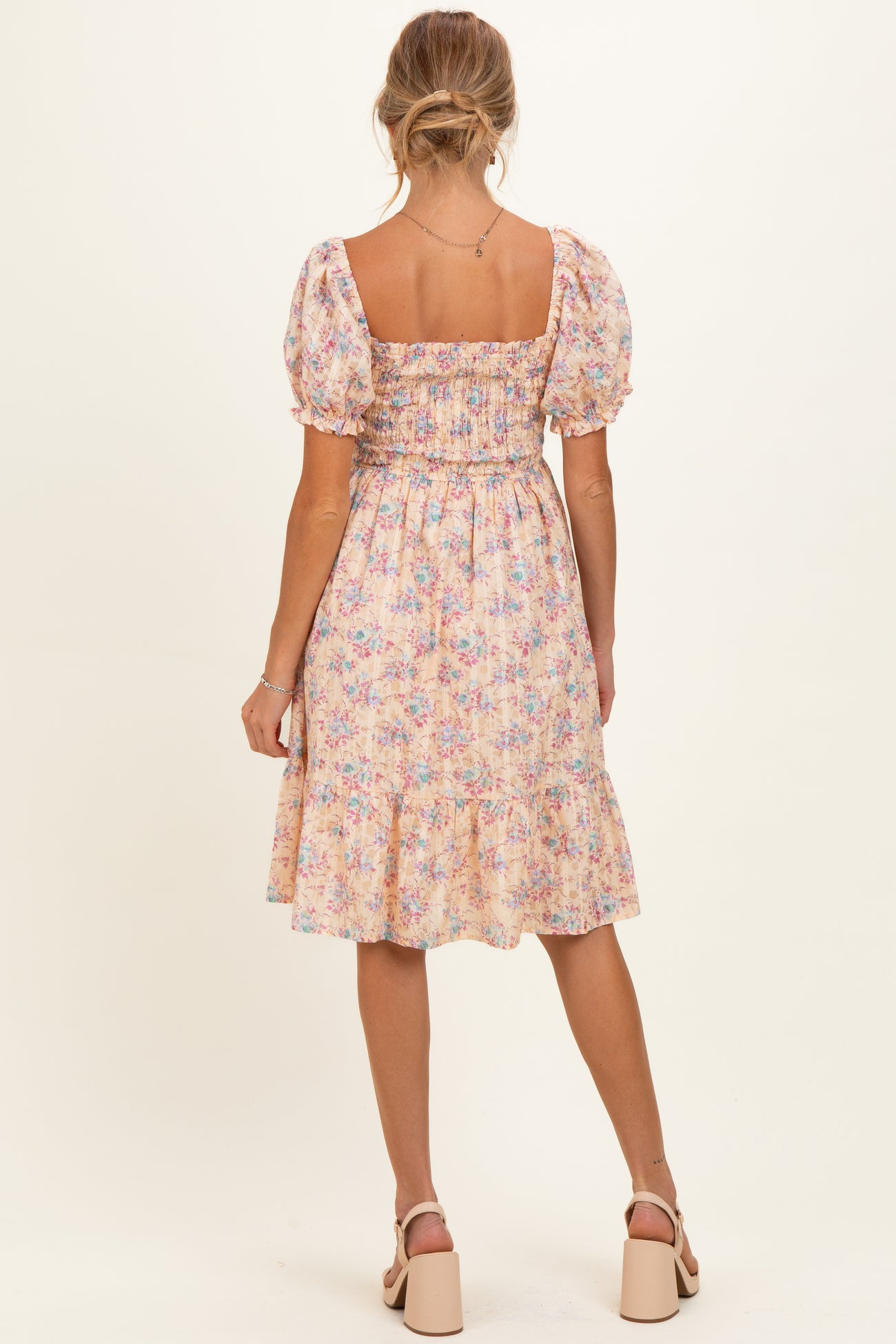 woman wearing a floral maternity dress with short puff sleeves and a smocked bodice, view from the back