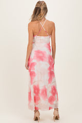 woman wearing a floral maternity maxi dress with pink flowers, showing the back and crisscross straps